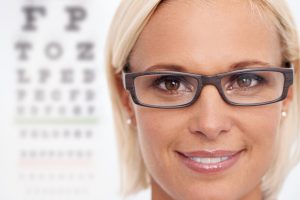 A photo of an Optometrist wearing glasses in front of a Snelldon's chart